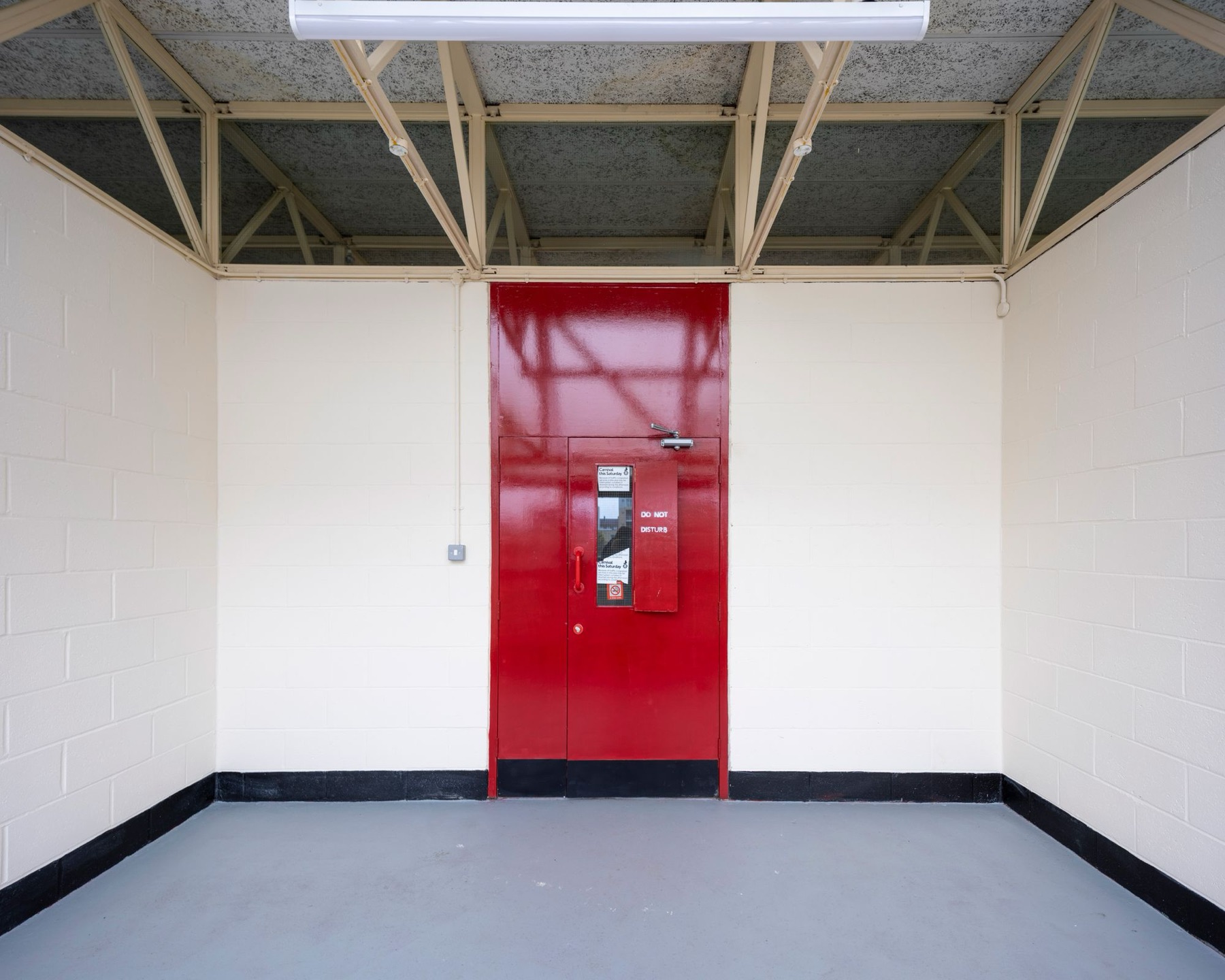 A studio with a glossy red door and cream trusses
