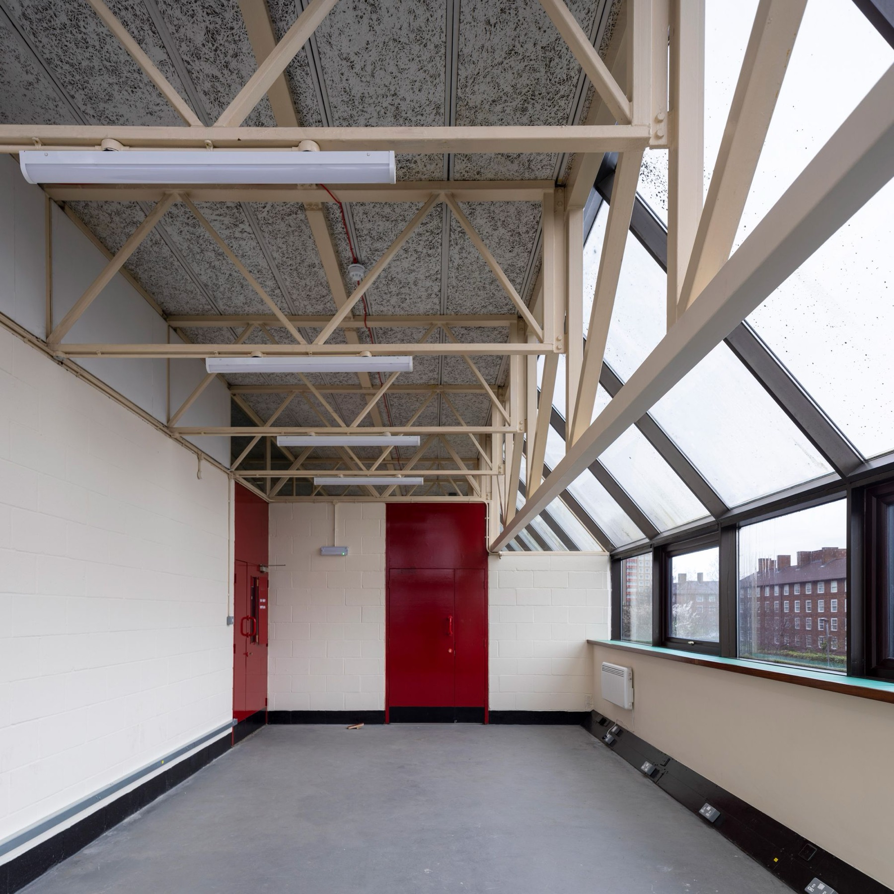 An empty studio with cream trusses and daylight through the sloped glazing